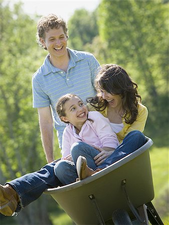 Man pushing his daughter and his wife in a wheelbarrow Stock Photo - Premium Royalty-Free, Code: 640-02764648