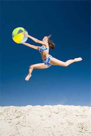 Young woman holding a beach ball and jumping Stock Photo - Premium Royalty-Free, Code: 640-02764704