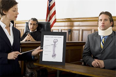 Female lawyer pointing at an exhibit in front of a judge and a victim Stock Photo - Premium Royalty-Free, Code: 640-02764737