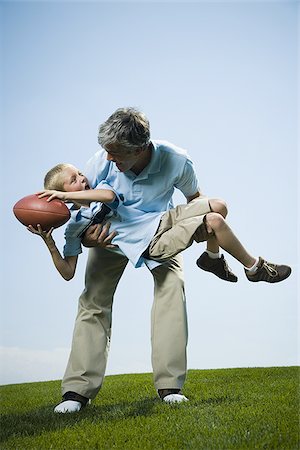 picture of father and son playing foot ball - Portrait of a man carrying his son Foto de stock - Sin royalties Premium, Código: 640-02764765