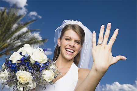 Portrait of a bride showing her wedding ring and smiling Stock Photo - Premium Royalty-Free, Code: 640-02764769