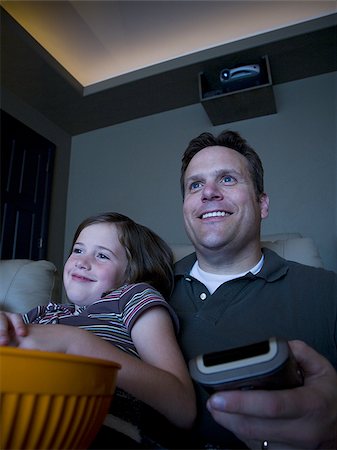 family watching tv together with popcorn - Father and daughters watching movie in home theater Stock Photo - Premium Royalty-Free, Code: 640-02764871