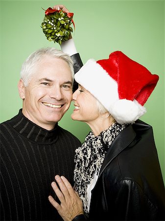 simsearch:640-03255756,k - A woman holds mistletoe over a man's head while kissing him on the cheek Stock Photo - Premium Royalty-Free, Code: 640-02764956