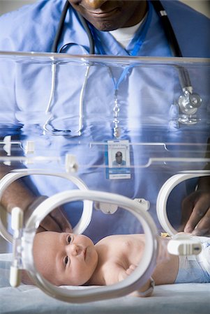 Bébé en couveuse avec un homme en uniforme Photographie de stock - Premium Libres de Droits, Code: 640-02765060