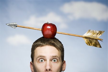 picture of man with arrow in head - Man outdoors with arrow through red apple on head Stock Photo - Premium Royalty-Free, Code: 640-02765175