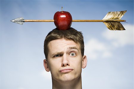 Man outdoors with arrow through red apple on head Stock Photo - Premium Royalty-Free, Code: 640-02765177