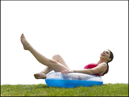 Woman in bikini lying in swimming ring on grass smiling Stock Photo - Premium Royalty-Free, Code: 640-02765217