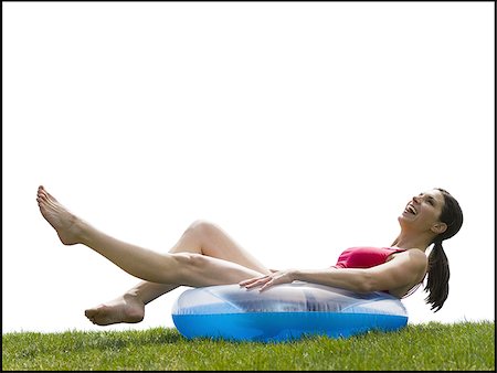Woman in bikini lying in swimming ring on grass smiling Stock Photo - Premium Royalty-Free, Code: 640-02765218