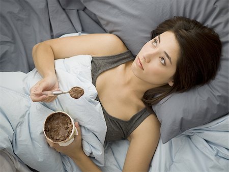 simsearch:640-02774723,k - Woman lying down in bed spilling chocolate ice cream on blanket Foto de stock - Sin royalties Premium, Código: 640-02765276