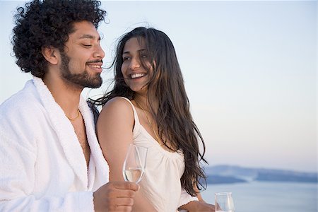 Couple sitting outdoors with champagne flutes and scenic background smiling and snuggling Stock Photo - Premium Royalty-Free, Code: 640-02765273