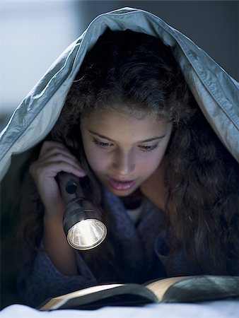 Girl laying in bed under blanket with flashlight reading Stock Photo - Premium Royalty-Free, Code: 640-02765328
