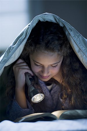 Girl laying in bed under blanket with flashlight reading Stock Photo - Premium Royalty-Free, Code: 640-02765329