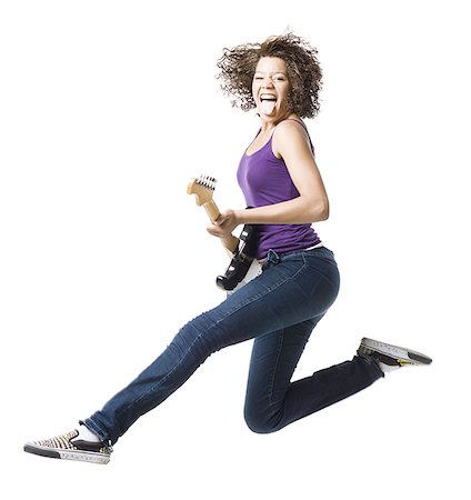 Girl with braces and guitar leaping and sticking tongue out Stock Photo - Premium Royalty-Free, Code: 640-02765363