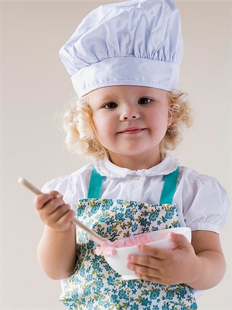 Little girl wearing a chef's hat and holding a bowl. Stock Photo - Premium Royalty-Free, Code: 640-02765522