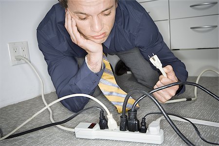 picture of man confused with cable - Close-up of a young man holding a plug Stock Photo - Premium Royalty-Free, Code: 640-02765714