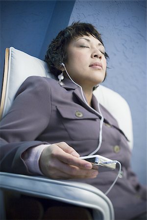 simsearch:640-02950853,k - Portrait of a businesswoman listening to an MP3 player with headphones Stock Photo - Premium Royalty-Free, Code: 640-02765778