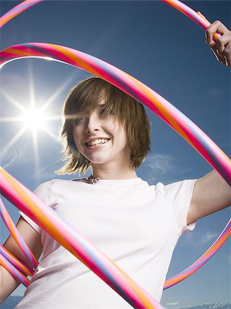Portrait of a teenage girl holding plastic hoops Stock Photo - Premium Royalty-Free, Code: 640-02765877