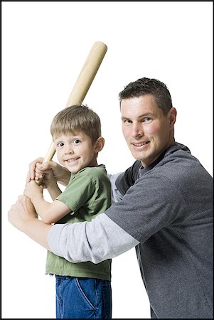 Portrait of a father teaching his son how to swing a baseball bat Stock Photo - Premium Royalty-Free, Code: 640-02765952
