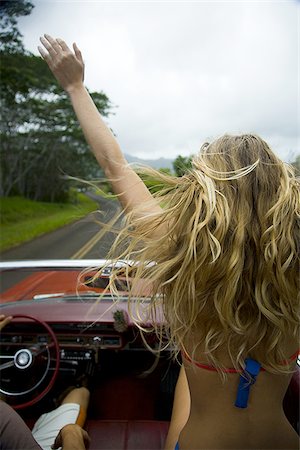 Rear view of a young woman sitting in a car with her hand raised Foto de stock - Sin royalties Premium, Código: 640-02766292