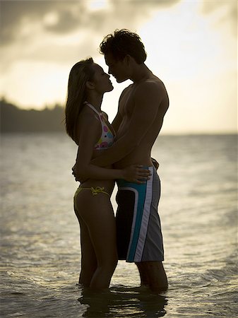simsearch:640-02769299,k - Jeune couple s'embrassant au coucher du soleil dans l'océan Photographie de stock - Premium Libres de Droits, Code: 640-02766383