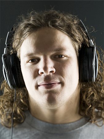 Close-up of a young man listening to the music on headphones Stock Photo - Premium Royalty-Free, Code: 640-02766439