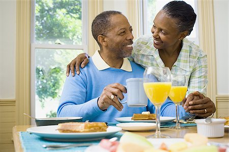 Senior man and a senior woman smiling at the breakfast table Stock Photo - Premium Royalty-Free, Code: 640-02766885