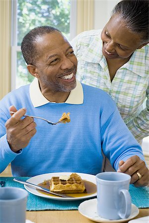 fat man tie - Close-up of a senior man having breakfast with a senior woman behind him Stock Photo - Premium Royalty-Free, Code: 640-02766897