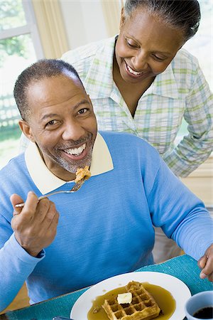 fat 60 year old man - Close-up of a senior man having breakfast with a senior woman behind him Stock Photo - Premium Royalty-Free, Code: 640-02766899