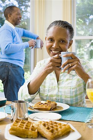 elderly black woman indoors - Close-up of a senior woman holding a cup of coffee with a senior man standing behind her Stock Photo - Premium Royalty-Free, Code: 640-02766913