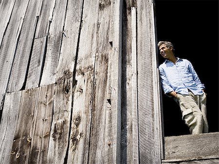 Low angle view of a man leaning against a wooden wall Foto de stock - Sin royalties Premium, Código: 640-02767111