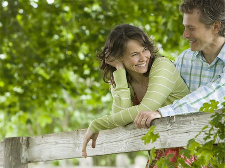 man and a woman leaning on a wooden fence Stock Photo - Premium Royalty-Free, Code: 640-02767216
