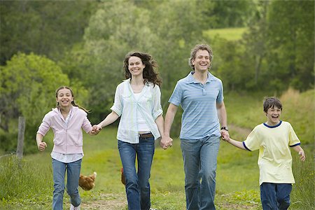 woman and a man with their son and daughter running in a field Stock Photo - Premium Royalty-Free, Code: 640-02767254