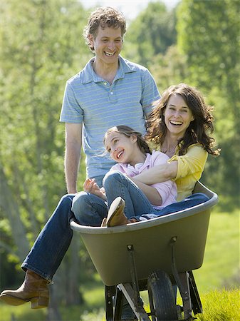 simsearch:640-02766847,k - woman and her daughter sitting in a wheel barrow with a man standing beside them Stock Photo - Premium Royalty-Free, Code: 640-02767303