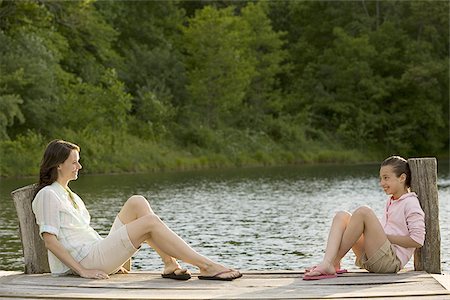 Profile of a woman and her daughter sitting face to face on a pier Stock Photo - Premium Royalty-Free, Code: 640-02767374