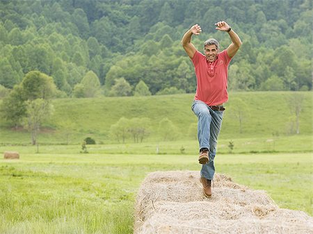 Portrait of a man jumping on a hay bale Stock Photo - Premium Royalty-Free, Code: 640-02767534