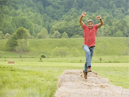 Portrait of a man jumping on a hay bale Stock Photo - Premium Royalty-Free, Code: 640-02767535