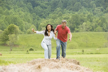 simsearch:640-03265364,k - Portrait of a man and a woman running on hay bales Stock Photo - Premium Royalty-Free, Code: 640-02767546