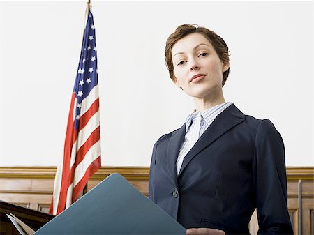 Portrait of a female lawyer standing in a courtroom and smiling Stock Photo - Premium Royalty-Free, Code: 640-02767844