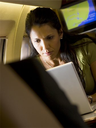 simsearch:640-02767934,k - Une femme d'affaires à l'aide d'un ordinateur portable dans un avion Photographie de stock - Premium Libres de Droits, Code: 640-02767937
