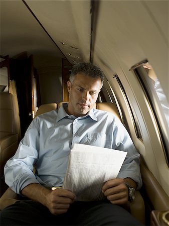 simsearch:640-02767934,k - Un homme lisant un journal dans un avion Photographie de stock - Premium Libres de Droits, Code: 640-02767931
