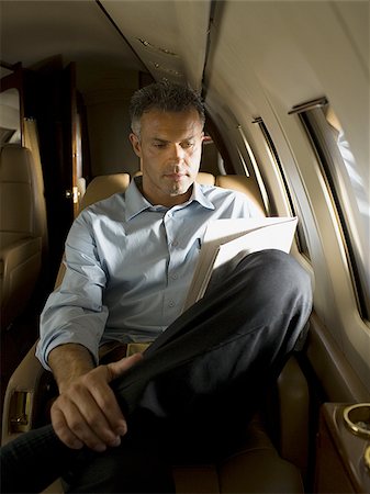 simsearch:640-02767934,k - Un homme lisant un journal dans un avion Photographie de stock - Premium Libres de Droits, Code: 640-02767932