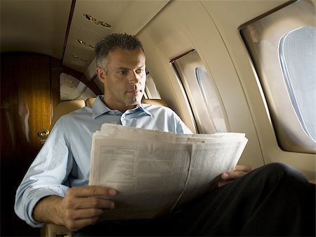 simsearch:640-02768050,k - Low angle view of a businessman reading a newspaper in an airplane Foto de stock - Royalty Free Premium, Número: 640-02767933