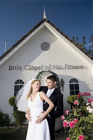 simsearch:640-01363514,k - Debout de couple de jeunes mariés devant une chapelle et souriant Photographie de stock - Premium Libres de Droits, Code: 640-02768008