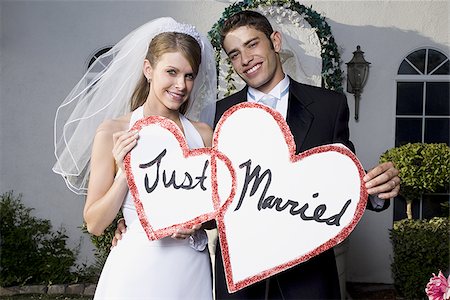 simsearch:640-01363514,k - Portrait d'un couple de jeunes mariés tenant une juste marié signe et souriant Photographie de stock - Premium Libres de Droits, Code: 640-02768009