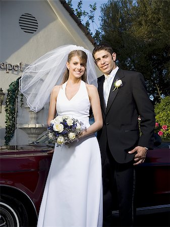Portrait of a newlywed couple standing near a car in front of a chapel Stock Photo - Premium Royalty-Free, Code: 640-02768018