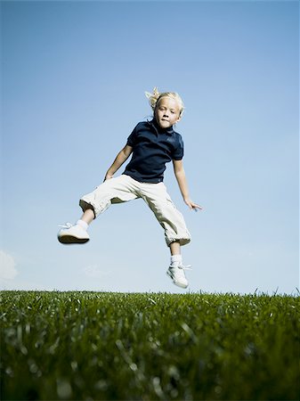 Vue d'angle faible d'une jeune fille sautant et souriant Photographie de stock - Premium Libres de Droits, Code: 640-02768039