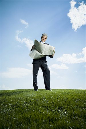 simsearch:640-02768050,k - Low angle view of a businessman reading a newspaper Foto de stock - Royalty Free Premium, Número: 640-02768047