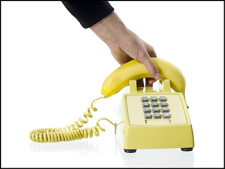 Close-up of a person's hand picking up a banana telephone receiver Stock Photo - Premium Royalty-Free, Code: 640-02768083
