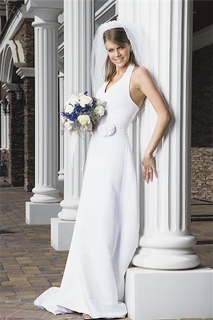 Portrait of a bride holding a bouquet of flowers and smiling Stock Photo - Premium Royalty-Free, Code: 640-02768098