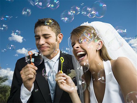Close-up of newlywed couple blowing bubbles with a bubble wand Stock Photo - Premium Royalty-Free, Code: 640-02768124